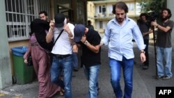 Turkish plainclothes police officers escort suspected members of the Islamic State (IS) group at a hospital for a medical check-up in Istanbul on July 24.