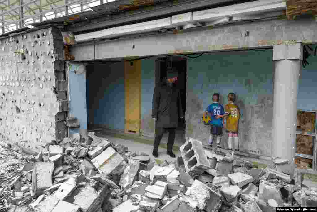 Киянин Дмитро Мельник стоїть біля малюнку вуличного художника Tvboy, на якому зображені двоє малих футболістів. Художник створив цей образ на стіні центрального стадіону Ірпеня, що постраждав під час нападу Росії на Україну, 29 січня 2023 року