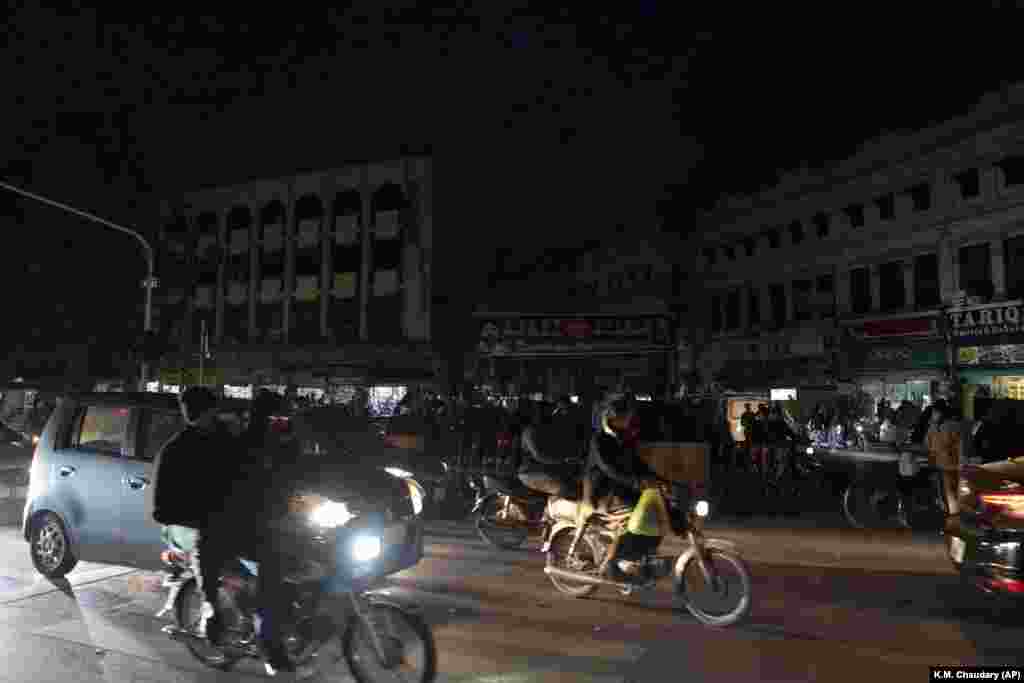 Motorcycles and cars pass a market in Lahore as the blackout continued into the evening. The electricity breakdown left many in the country of 220 million people without drinking water as pumps powered by electricity failed to work. Schools, hospitals, factories, and shops were without power amid the harsh winter weather.