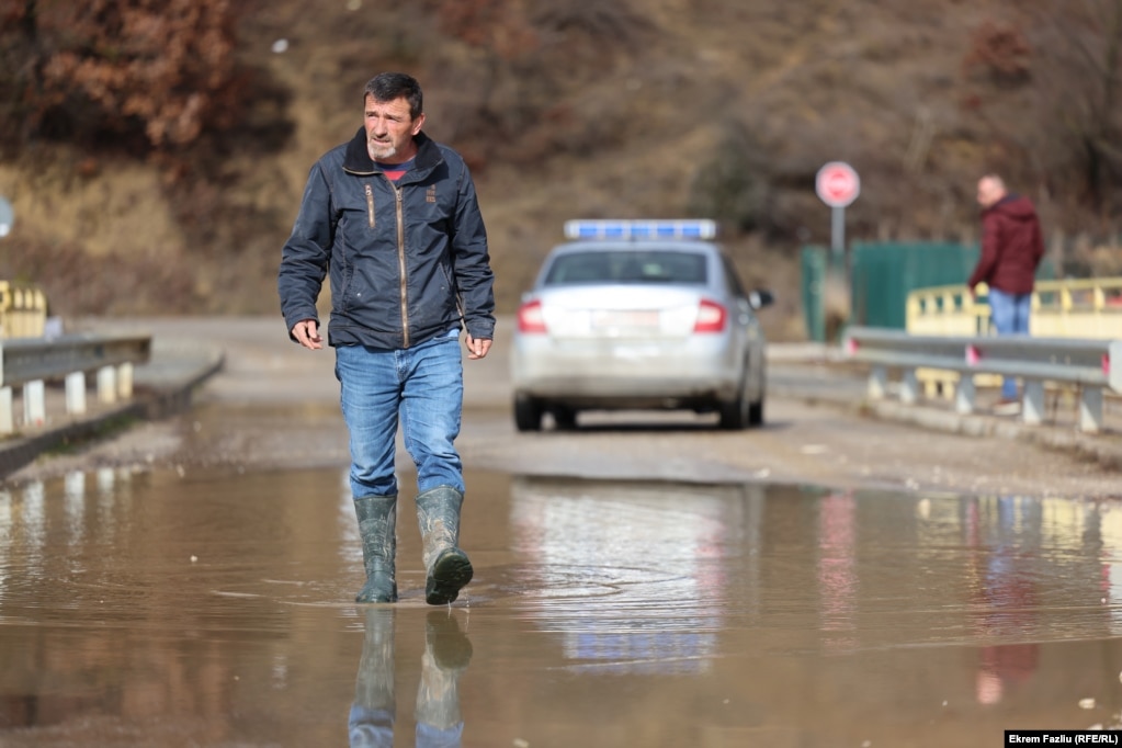 Një qytetar duke lëvizur me çizme gome në një rrugë të përmbytur, në Llaushë.