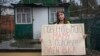 Alina Kapacina egy plakátot tart a kezében, amelyen ez áll: „Hozzátok vissza anyámat a fogságból. Olenivka”