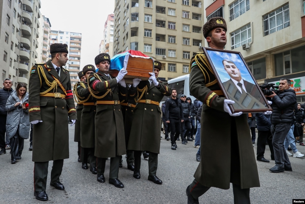 Honor guards carry a portrait and a coffin with the body of Orkhan Askerov, a security officer at Azerbaijan's embassy in Iran shot dead by a gunman, during a procession prior to his funeral in Baku on January 30.