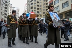 Honor guards carry a portrait and a coffin with the body of Orkhan Askerov, a security officer at Azerbaijan's embassy in Iran shot dead by a gunman, during a procession prior to his funeral in Baku on January 30.