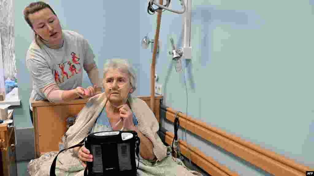 Tetyana Venglinszka segít a hasonló helyzetben lévő 75 éves, tüdőrákban szenvedő édesanyjának, Evának beállítani az oxigént egy kijevi hospice-ban