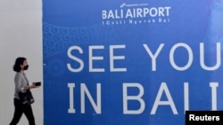  Пътник минава около поздравителен афиш на интернационалното летището Нгура Рай в Денпасар, Бали 