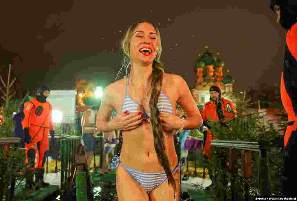 A woman in a bikini smiles after walking out of the icy waters of a pond in Moscow.
