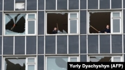 Люди чистят разбитые стекла в здании, поврежденном в результате российского ракетного удара по Львову. 4 мая 2022 года