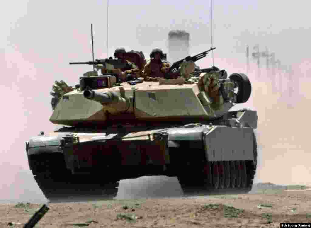 Një tank M1A1 Abrams i ushtrisë amerikane duke lëvizur me shpejtësi nëpër një autostradë irakiane, afër një pike ushtarake kontrolli, në Falluxha, më 1 korrik 2004. Ushtria amerikane besohet të ketë në përdorim 2.509 tanke Abrams të versioneve të ndryshme, si dhe 3.700 tanke Abrams në magazina.