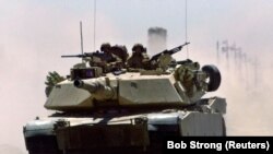 Танк M1 Abrams морской пехоты США мчится по иракскому шоссе возле военного контрольно-пропускного пункта в Эль-Фаллудже, 1 июля 2004 года.