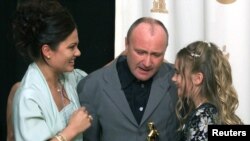Фил Колинс прегръща жена си и дъщеря си Лили след получаването на Оскар за най-добра филмова песен, Лос Анджелис, 26 март 2000 г.