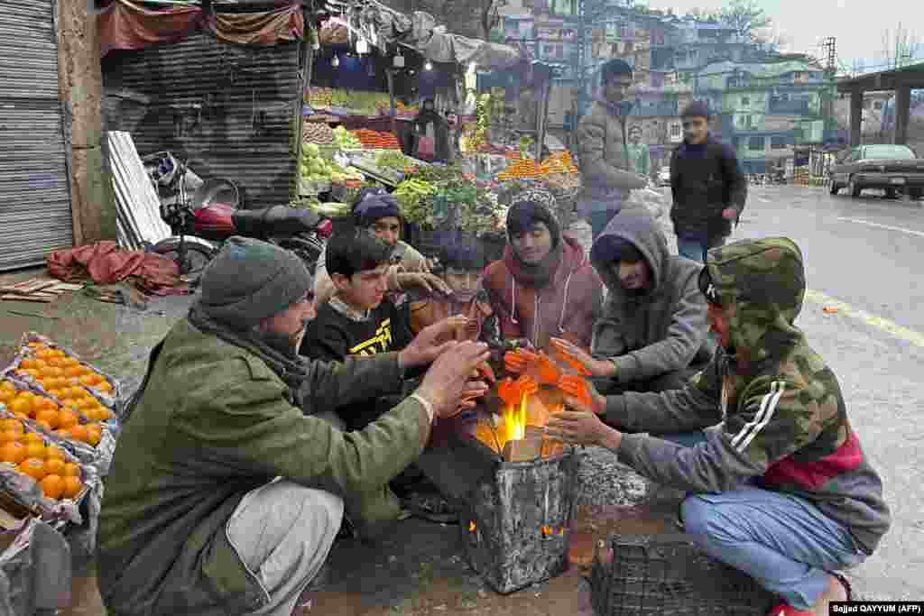 Vendors warm themselves over a fire at a market in Muzaffarabad during a nationwide power outage on January 23. Officials say most of Pakistan was struck by a power outage as an energy-saving measure by the government backfired.