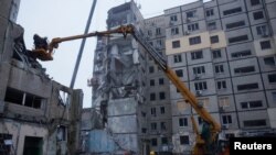 Аварийни служители работят на мястото, където жилищен блок беше силно повреден от руски ракетен удар в Днипро, 16 януари 2023 г.
