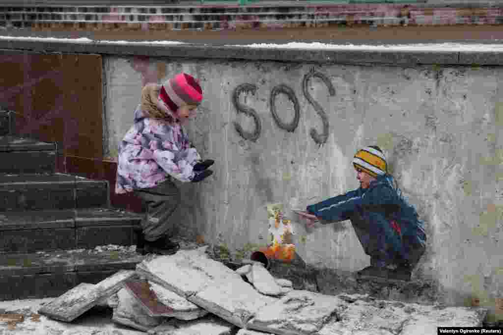 4-річна Анастасія біля вогнища разом із хлопчиком &ndash; витвором мистецтва відомого вуличного художника Tvboy у центрі Бучі. Україна, 29 січня 2023 року