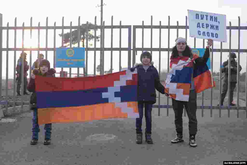 Armenians with a poster reading &quot;Putin! Keep Your Word&quot; stand in front of Russian peacekeepers at a checkpoint outside of Stepanakert on December 27.&nbsp; &nbsp;