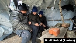 Ukrainian children attend an online class in a makeshift classroom built by them from wooden poles and plastic sheeting in a village in the Kharkiv region. (file photo)