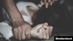 Мужчина держит женщину за руки, чтобы произвести сексуальное насилие. Иллюстративное фото