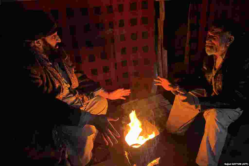 People warm themselves next to a fire in Muzaffarabad. Pakistan is grappling with one of its worst economic crises in recent years amid dwindling foreign-exchange reserves, which has compelled the government to order shopping malls and markets to close by 8:30 p.m. to conserve energy.