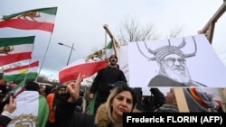 تصویر یکی از کاریکاتورهای منتشر شده از خامنه‌ای در شارلی ابدو در دست یکی از معترضان مقابل پارلمان اروپا
