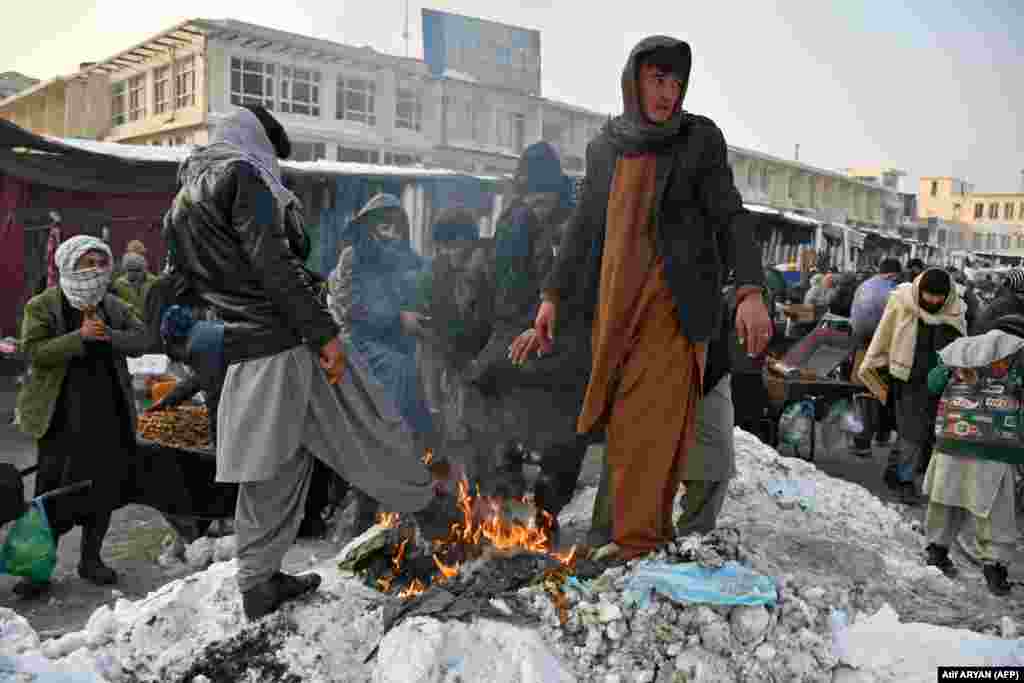 Афганские мужчины греются у костра на рынке в Мазари-Шарифе, 14 января