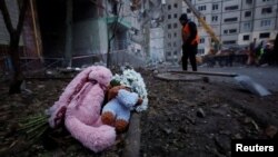 Местни хора оставиха плюшени играчки и цветя пред разрушения от руска атака блок в Днипро, Украйна