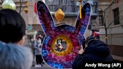 Mališan pozira za fotografiju uz cvetni ukras u obliku zeca u pešačkoj trgovačkoj ulici prvog dana praznika lunarne Nove godine u Pekingu, u nedelju, 22. januara 2023.