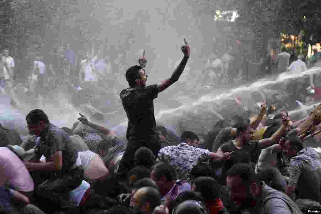 Protesters gesture rudely as riot police use water cannons in an effort to disperse them during a rally against a recent decision to raise public electricity prices in Yerevan on June 23. Armenian police say 237 people were arrested. Seven demonstrators and 11 police officers were injured in the clashes, with three protesters being hospitalized. (Reuters/Vahram Baghdasaryan/Photolure)