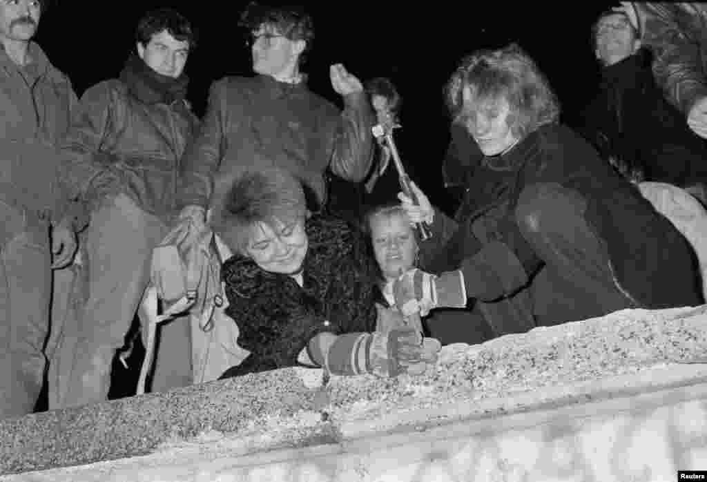 Berliners take a hammer and chisel to a section of the Berlin Wall in front of the Brandenburg Gate after the opening of the East German border was announced on&nbsp;November 9, 1989. 