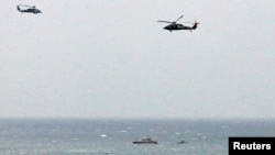 An Iranian Revolutionary Guard boat is seen near the U.S. aircraft carrier, USS George H. W. Bush while transiting Straits of Hormuz as U.S. Navy helicopters hover above it, March 21, 2017