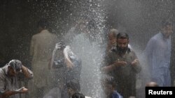 People cool off in spray from a leaking pipe during Karachi's 2015 heat wave.