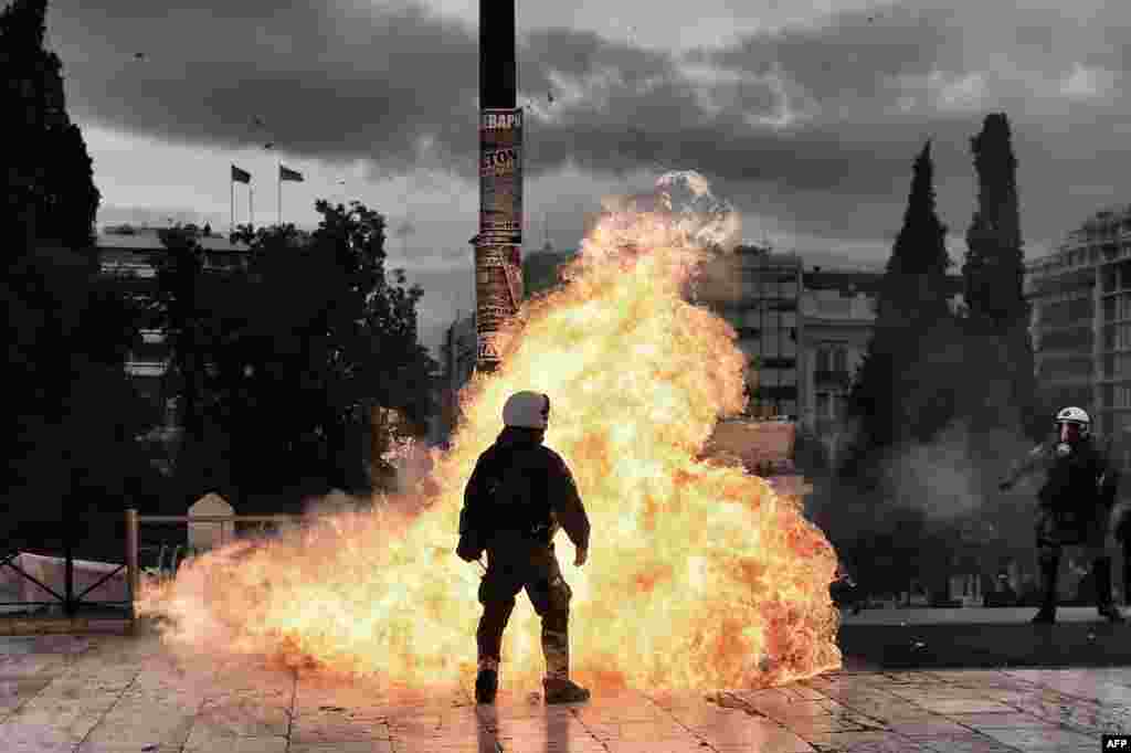 A firebomb explodes beside a riot policeman during a massive protest in Athens on February 4. (AFP/Aris Messinis)