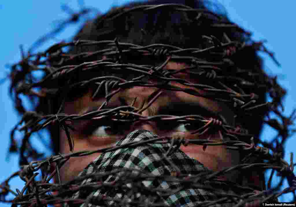 A masked Kashmiri man with his head covered in barbed wire attends a protest on October 11 following the scrapping of Kashmir's special constitutional status by the Indian government. (Reuters/Danish Ismail)