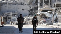 Fighters of the Syrian Democratic Forces walk along a road in Raqqa. 