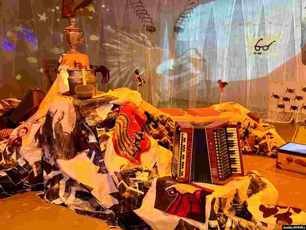 Күргәзмәгә килеп керү белән карлы тауларны хәтерләткән кәгазь өемнәренә тап буласың. Бу себер урманарын, тауларын, сикәлтәле юлны хәтерләтә, юл буеннан атлаганда татар чүәкләре, сандык, чемодан, тимер кашыклар, Тукай рәсеме, самовар, гармун, китаплар, йөк машинасын очратасың…