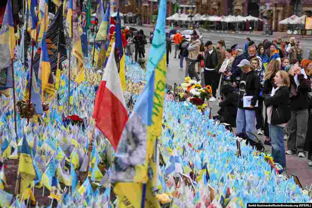 Люди, які прийшли вшанувати пам&#39;ять полеглих українських захисників. Деякі взяли з собою портрети своїх рідних та близьких, які загинули на війні, та запалили лампадки біля меморіалу з прапорцями на Майдані Незалежності у Києві