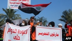 Iraqi students carry banners as they march during ongoing anti-government demonstrations in the capital Baghdad's Tahrir square, on December 22, 2019. (Photo by SABAH ARAR / AFP)