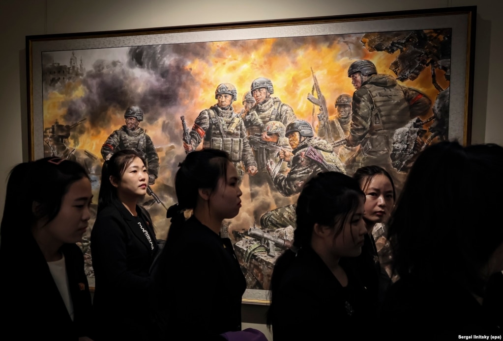 Turistet koreanoveriore duke ecur para një pikture të titulluar “Luftëtarët heroikë për dinjitetin dhe nderin e atdheut”.