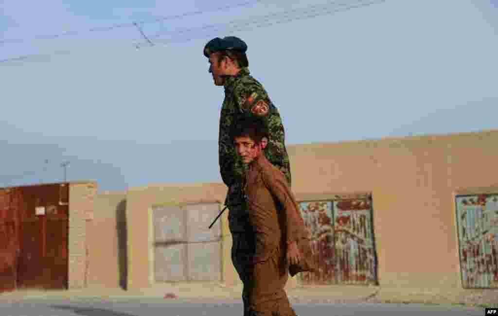 A wounded Afghan boy walks with a soldier at the site of a suicide attack near Mazar-e Sharif, on February 8. (AFP/Farshad Usyan)