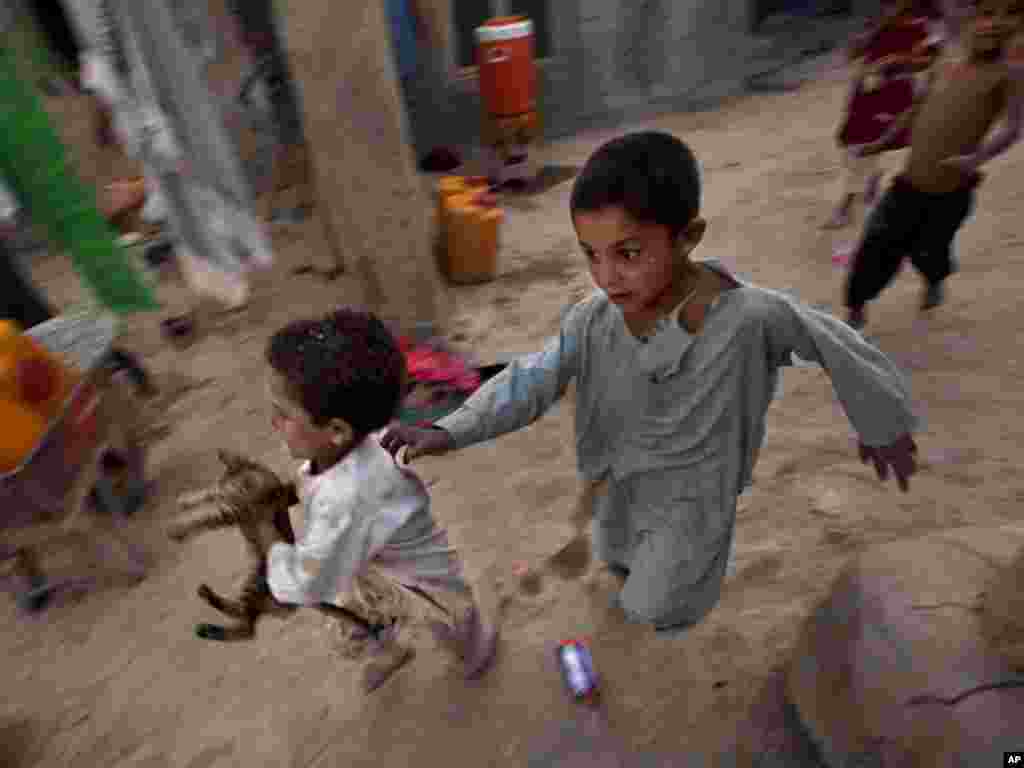 Riyaz Ahmed (left), an internally displaced Afghan boy, runs away with a kitten he caught near his impoverished house at a refugee camp in Kabul, Afghanistan, on August 9. According to UN, some 2.7 million registered Afghans refugees remain in Pakistan and Iran.Photo by Dar Yasin for AP