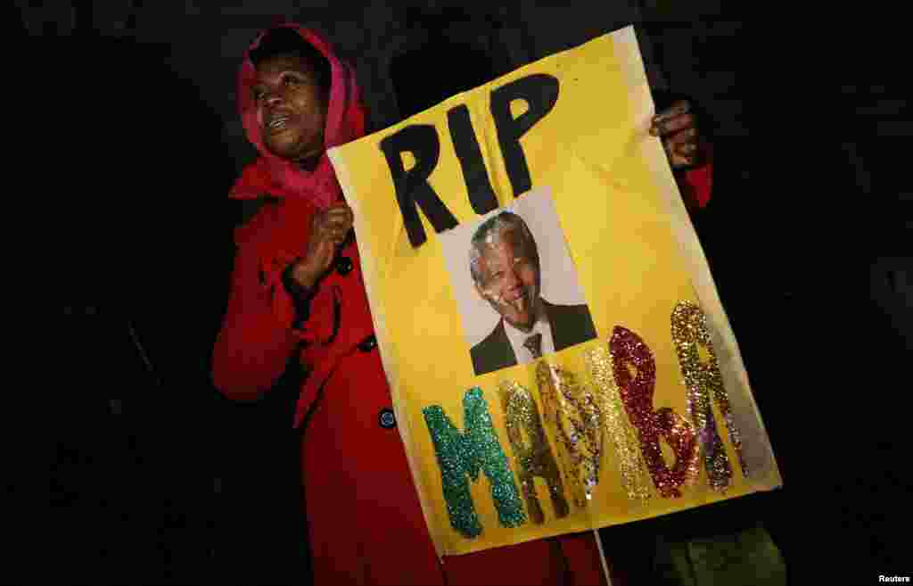 A woman holds a sign at a gathering in memory of Nelson Mandela outside the South African High Commission across from Trafalgar Square in London. (Reuters/Suzanne Plunkett)