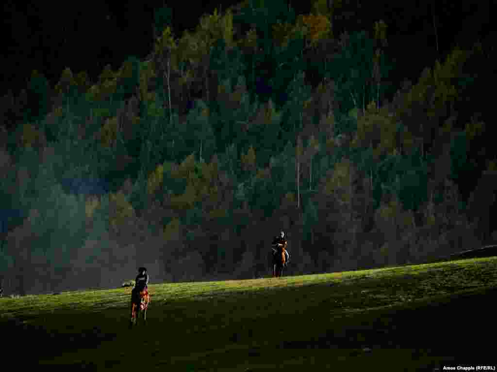 Horsemen wandering toward an event. In the mountains of Kyrgyzstan, the first touch of autumn is coloring the trees.&nbsp;