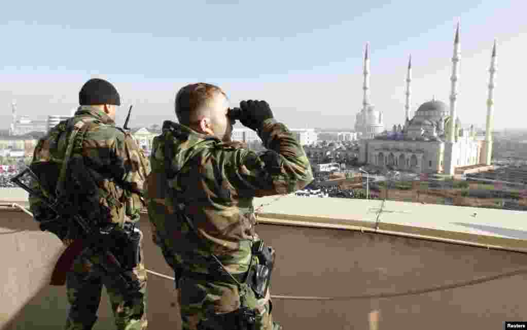 Members of the security forces keep watch from a nearby rooftop.