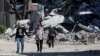 Местные жители проходят мимо разрушенного здания в Мариуполе, 12 мая 2022 года