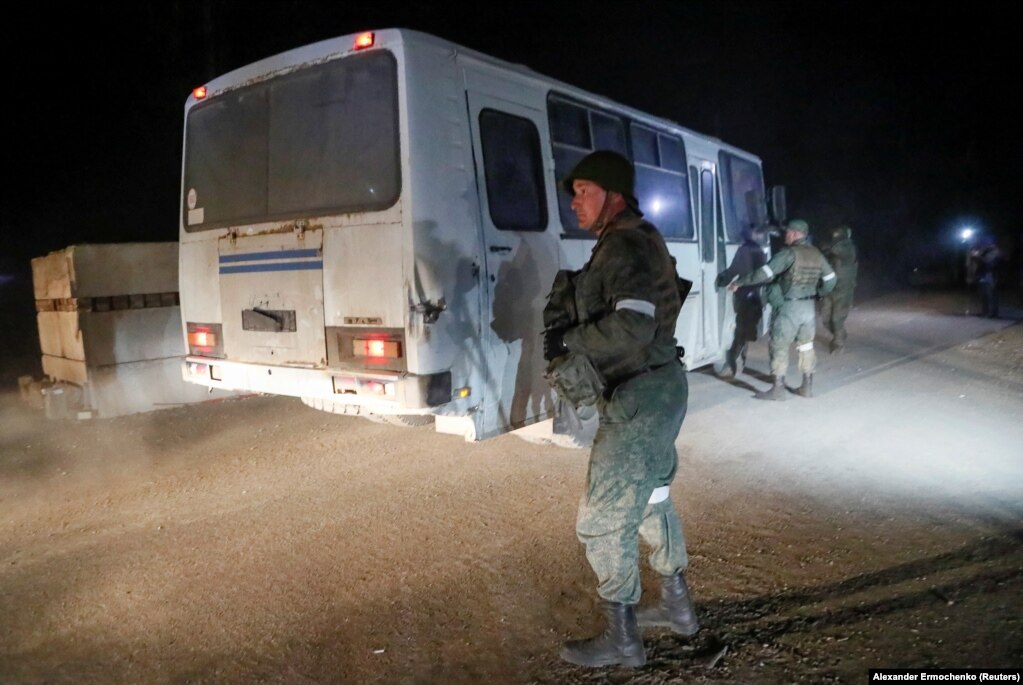 A separatist soldier watches as a bus carrying Ukrainian forces from the besieged Azovstal steel plant in Mariupol arrives in Novoazovsk on May 16.