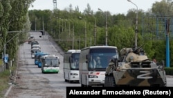 Buses carrying Ukrainian soldiers who surrendered after weeks holed up at the Azovstal steel works drive away under escort of Russia's forces in Mariupol on May 17.