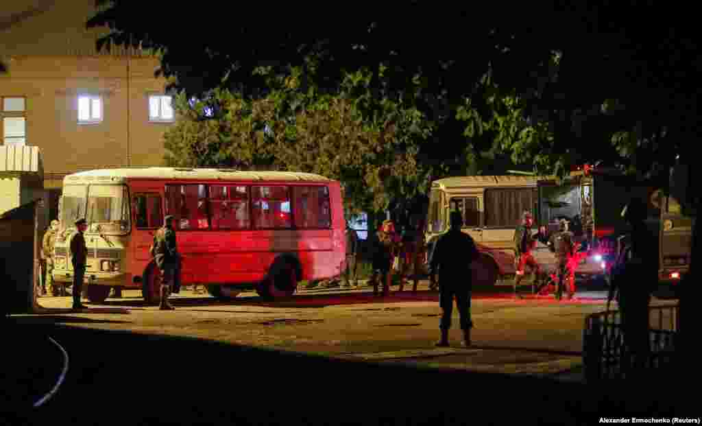 Soldați separatiști fac de gardă în timp ce autobuzele care transportă militari ucraineni răniți de la Mariupol sosesc la Novoazovsk.