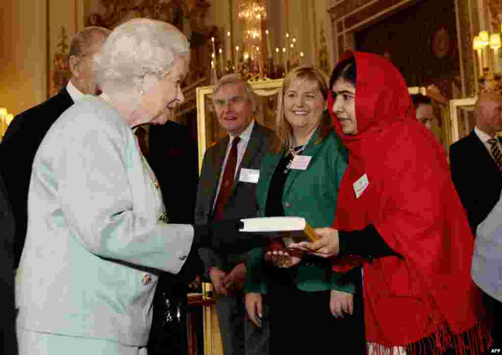 Malala Jusafzai (desno) daje primerak svoje knjige kraljici Elizabeti II tokom prijema za mlade, obrazovanje i Komonvelt u Bakingemskoj palati u Londonu, 18. oktobra 2013. &nbsp;