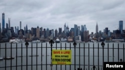 Табличка, напоминающая о важности соблюдения социальной дистанции, на заднем плане — вид на Манхэттен, Нью-Йорк, 3 апреля 2020 года.