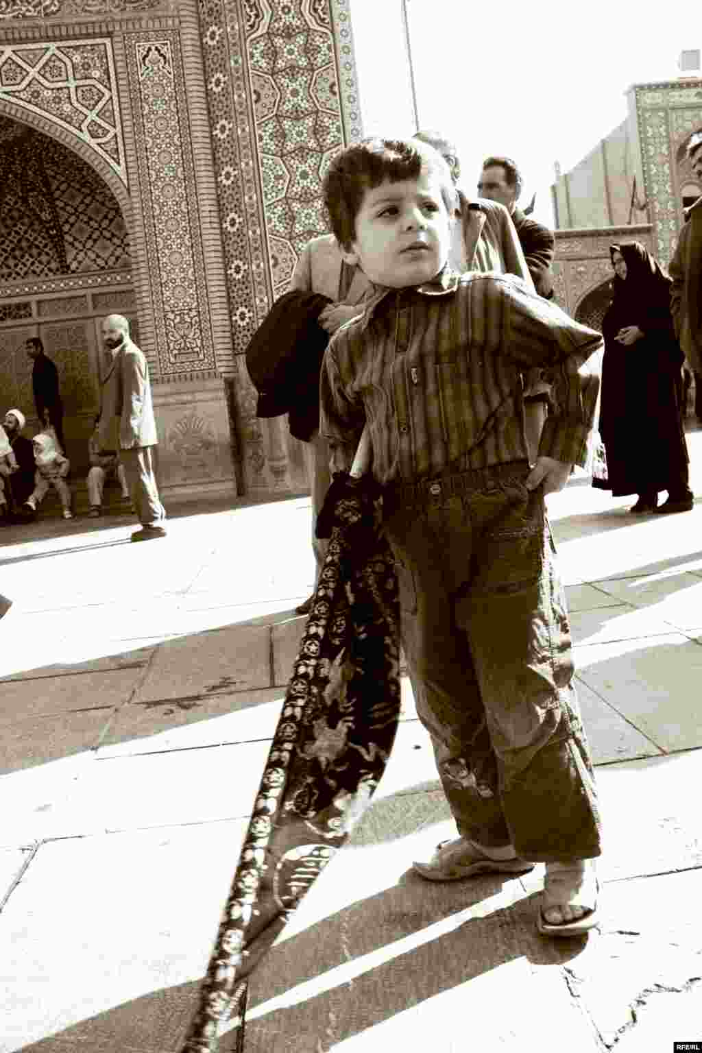 Pilgrims, including children, recite prayers for martyred imams outside the shrine.
