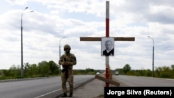 Портрет президента России Владимира Путина с крестом, изображающим его могилу, на блокпосту под Днепром во время вторжения России в Украину, 10 мая 2022 года