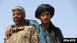 An Afghan Taiban militant poses for a picture with an army soldier during the brief cessation of hostilities earlier this month.